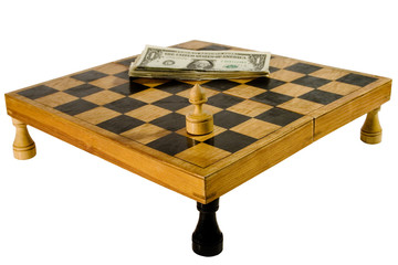 Old chessboard resting upon the rooks, with a pawn and dollars