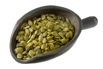 roasted pumpking seeds (pepita) on wood scoop,  isolated