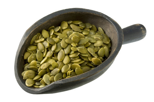 roasted pumpking seeds (pepita) on wood scoop,  isolated
