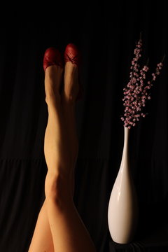Female legs and vase with flowers in the background