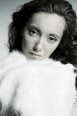 attractive woman in white furs over grey background