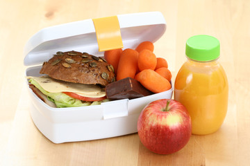 box with sandwich fruits and chocolate and bottle of juice