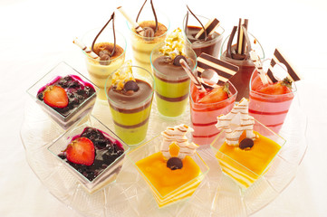 An assortment of colorful mousse desserts in cups.