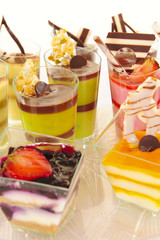 An assortment of colorful mousse desserts in cups.