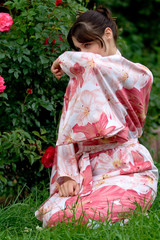 Girl in a pink yukata near rosebush.