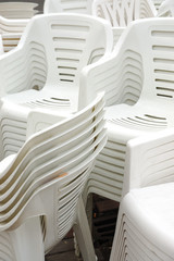 Stack of white plastic chairs on the street
