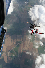 Two skydivers exit a plane in a sit position