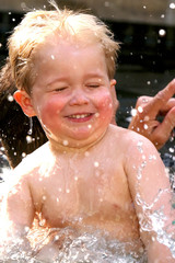 Cute little boy with blond hair swimming in a pool