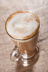 coffee latte with closeup froth on rustic, shallow DOF