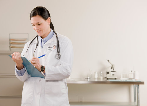 Confident female doctor writing on medical chart