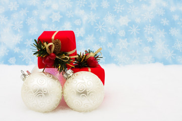 Silver glass Christmas balls with red presents on snow
