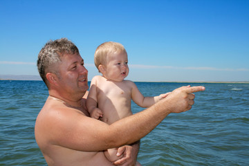 Father and his son look into the side on the beach