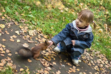Little girl with two funny ponytails feeds small squarell