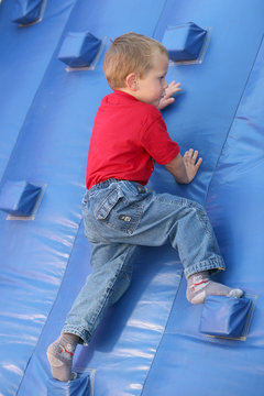 Petit garçon montant à un mur d'escalade gonflable
