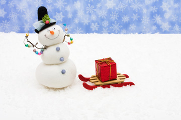 Wooden sleigh sitting on snow with red Christmas present