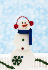 Snowman and white picket fence with green garland