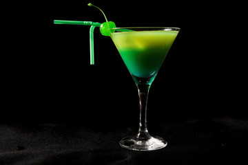 green cocktail with cherry isolated on black
