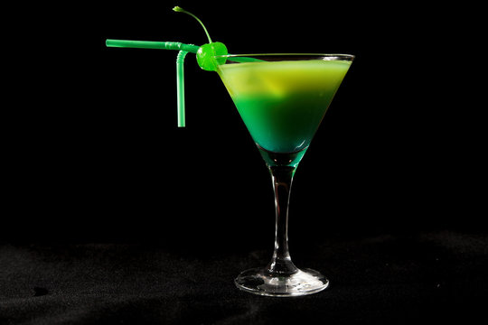 green cocktail with cherry isolated on black