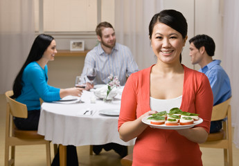 Woman holding appetizer and serving friends at dinner party