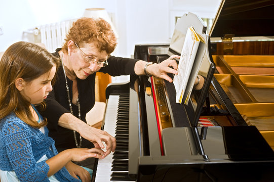 Senior Piano Teacher With Young Girl Student