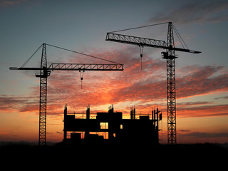 Two cranes build construction over sunset - 9698620