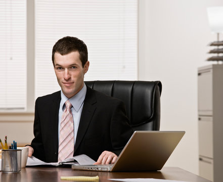 Confident businessman working on laptop at desk