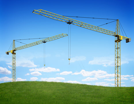 Two cranes over green hill