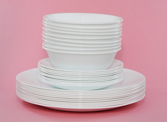 white bowls and plates stacked, pink background