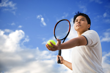 A young sporty asian male playing tennis outdoor