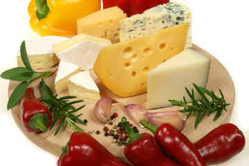 Cheese, peppers and herbs on a wooden board.