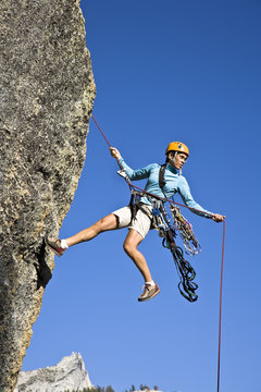 Female rock climber rappelling.