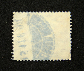 Blank postage stamp with postmark on black background