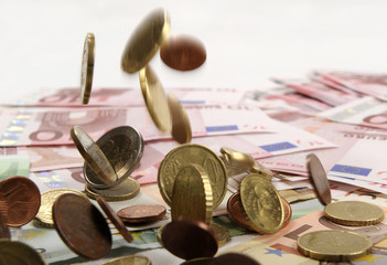 Euro coins falling on euro banknotes, isolated