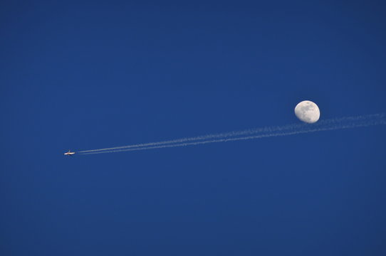 Contrail from a small plane underneath a full moon