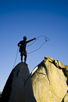 A rock climber celebrates on the summit of a rock spire.
