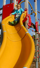 petite fille sur le toboggan jaune de l'aire de jeux