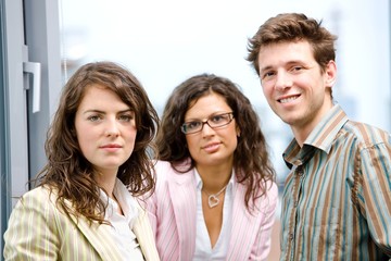 Happy young businesspeople talking in front of office window,