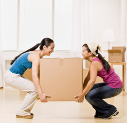 Women moving into new home and carrying large cardboard box