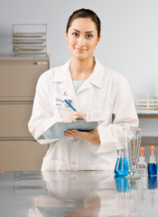 Scientist in lab coat writing on clipboard in laboratory
