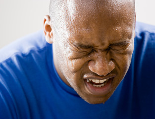 Fatigued man dripping sweat and grimacing