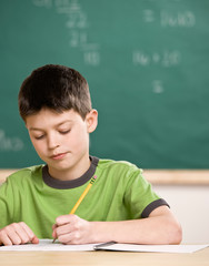 Concentrating student writing in notebook in school classroom