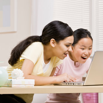 Excited sisters use laptop for internet together