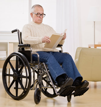 Disabled man in wheelchair enjoying reading a book