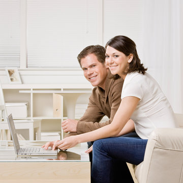 Happy couple typing on laptop in livingroom