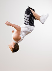 Skilled athlete in sportswear doing somersault in mid-air - obrazy, fototapety, plakaty