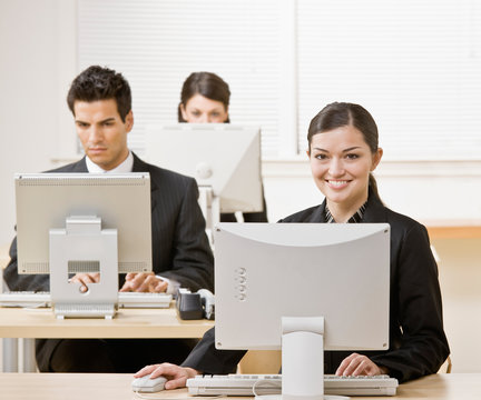 Businesswoman working on computer with co-workers