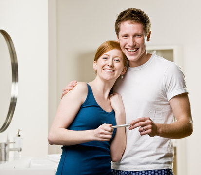 Happy couple in bathroom viewing positive pregnancy test