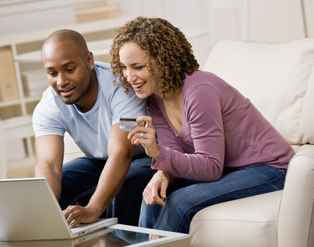 Happy couple using credit card to shop online conveniently