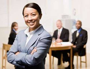 Confident businesswoman with co-workers in background