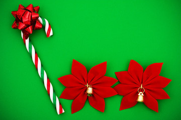 Candy cane with red bow and poinsettia on green background